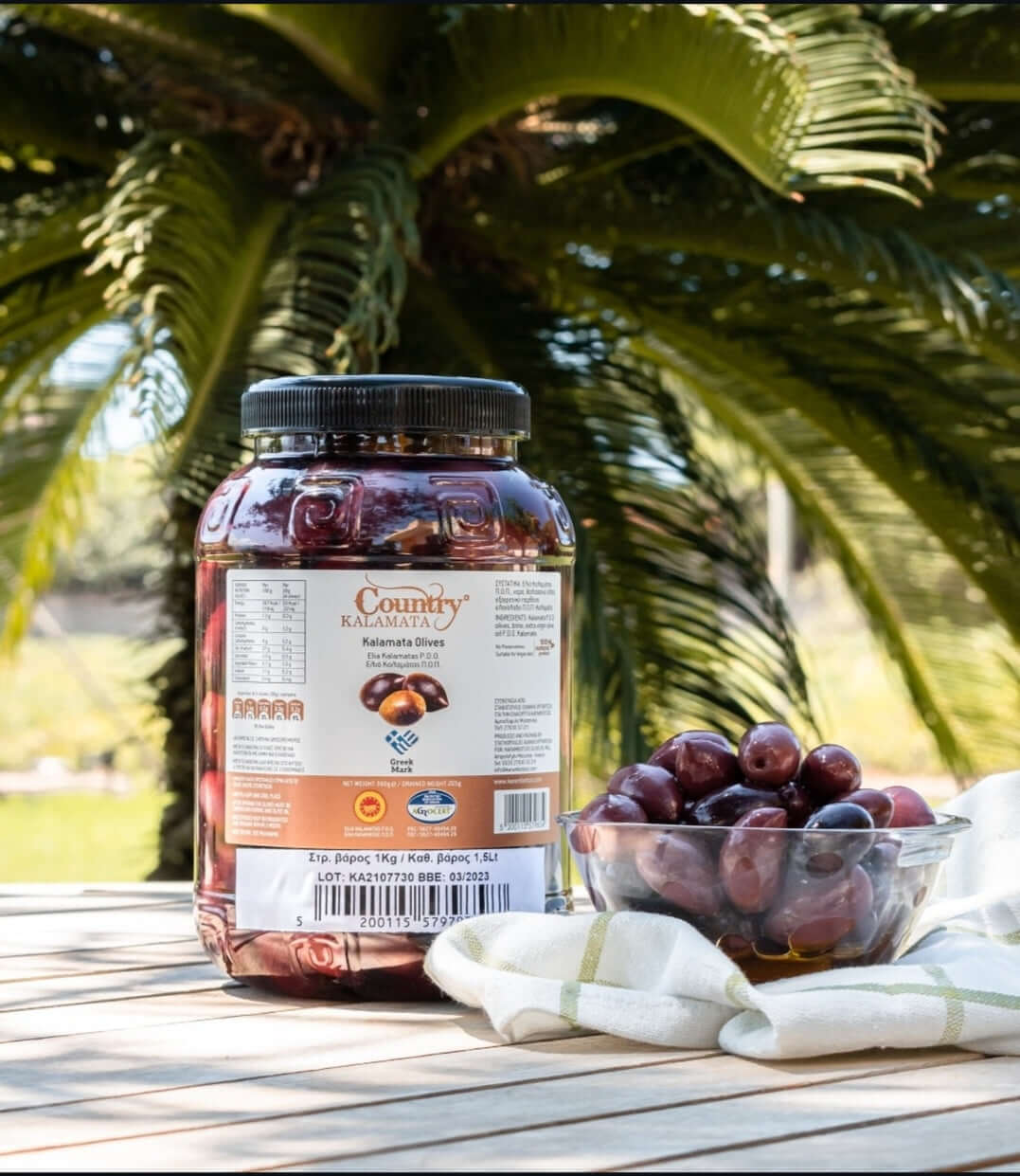 Country Kalamata olives 1.5LT jar with a bowl of olives on a table, showcasing premium Greek quality and flavor.